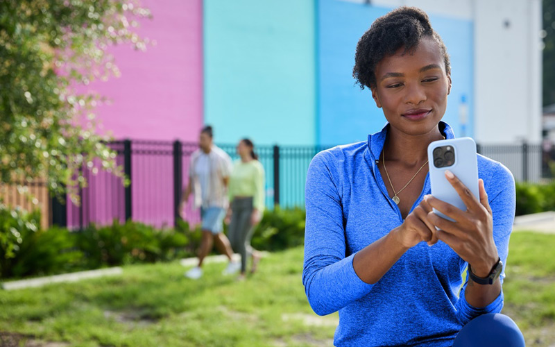 Woman outdoors standing on grass and looking at mobile phone